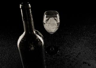 Cork pulled from a bottle, resting beside a half-filled glass of red wine